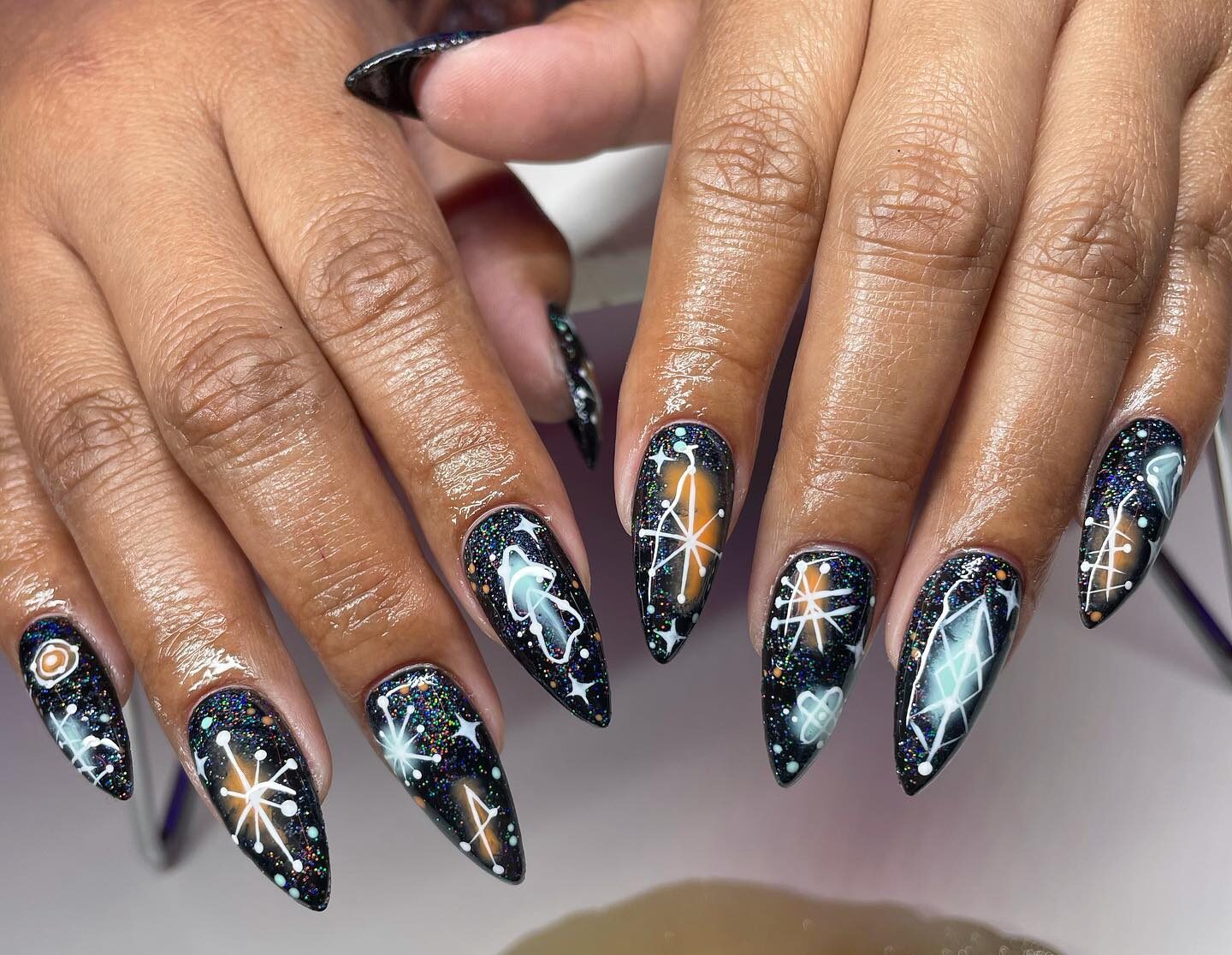 Black nail polish with celestial nail art and glitters on long stiletto nails