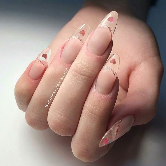 Long round shaped clear nails with light pink hearts on the tips