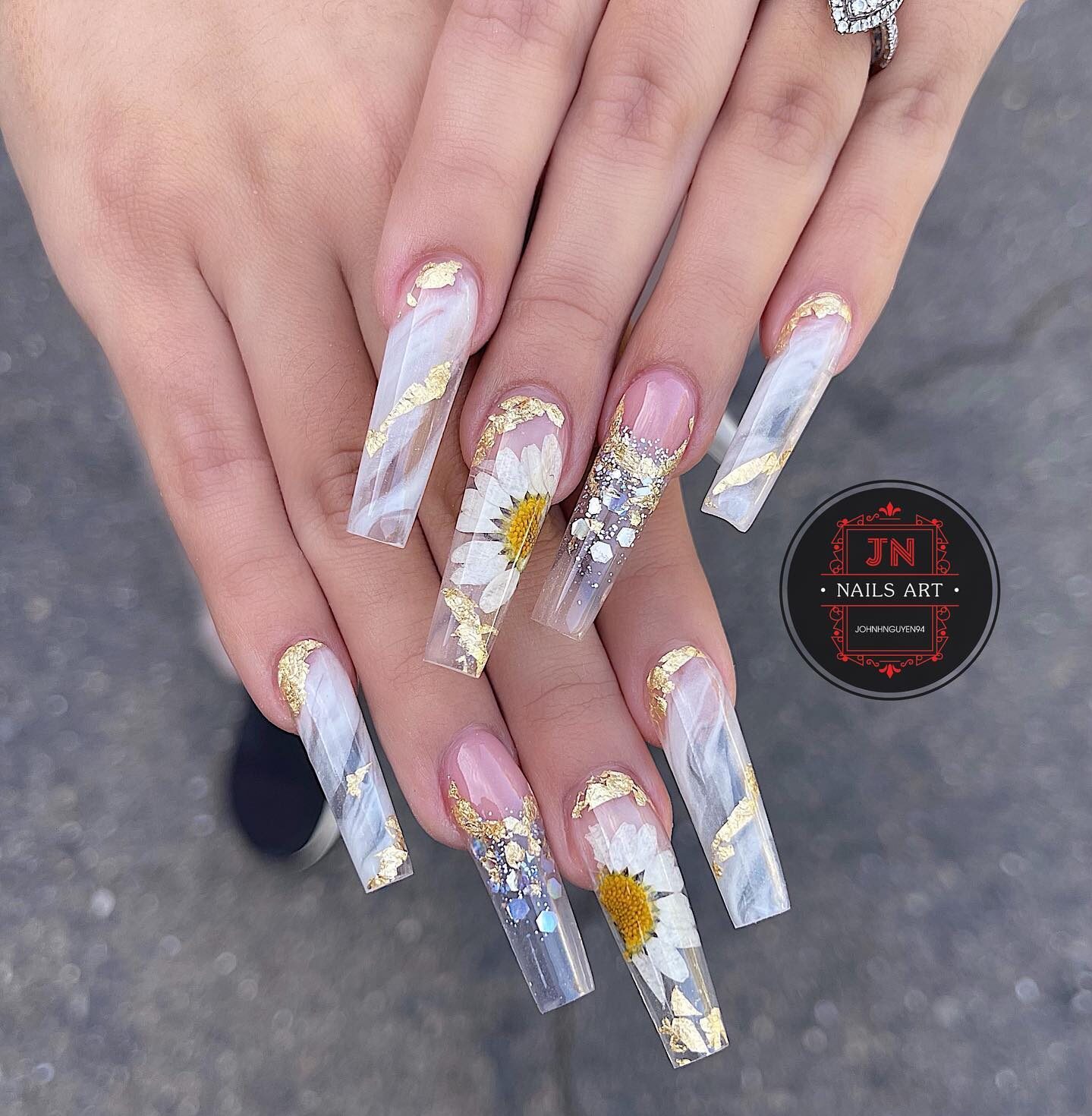 Marble nail design with gold foil, glitters, and daisy flowers nail arts on long tapered square clear nails