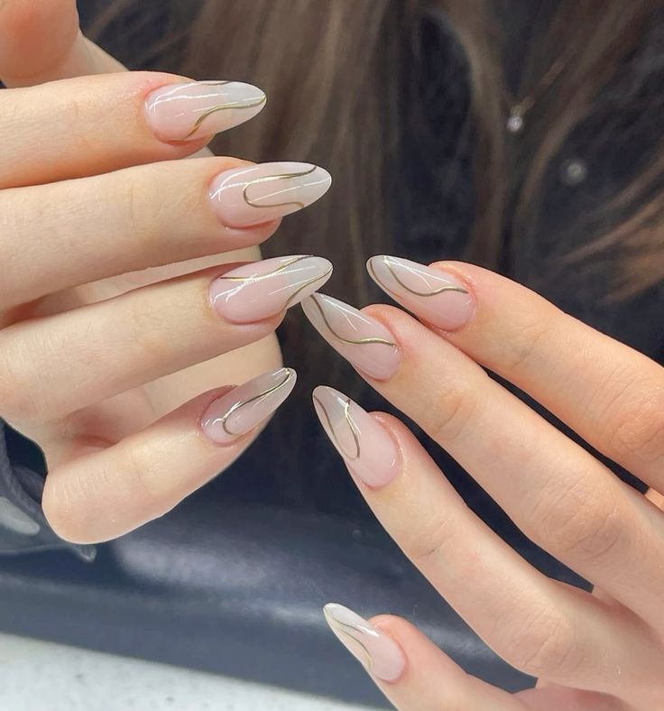 Clear almond nails with thin gold swirling patterns