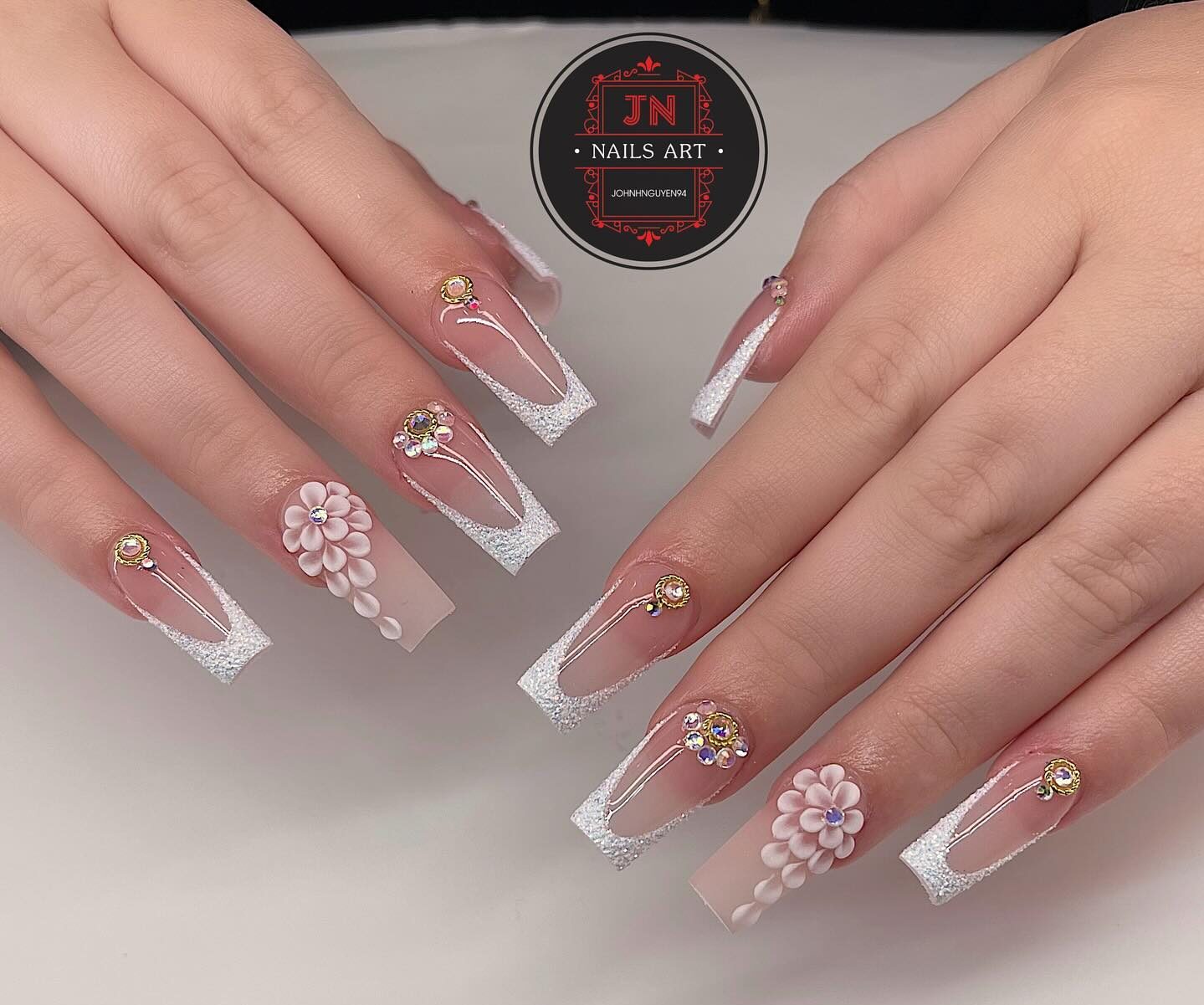 3D flower designs, rhinestones, and shimmering French tips on long square clear nails