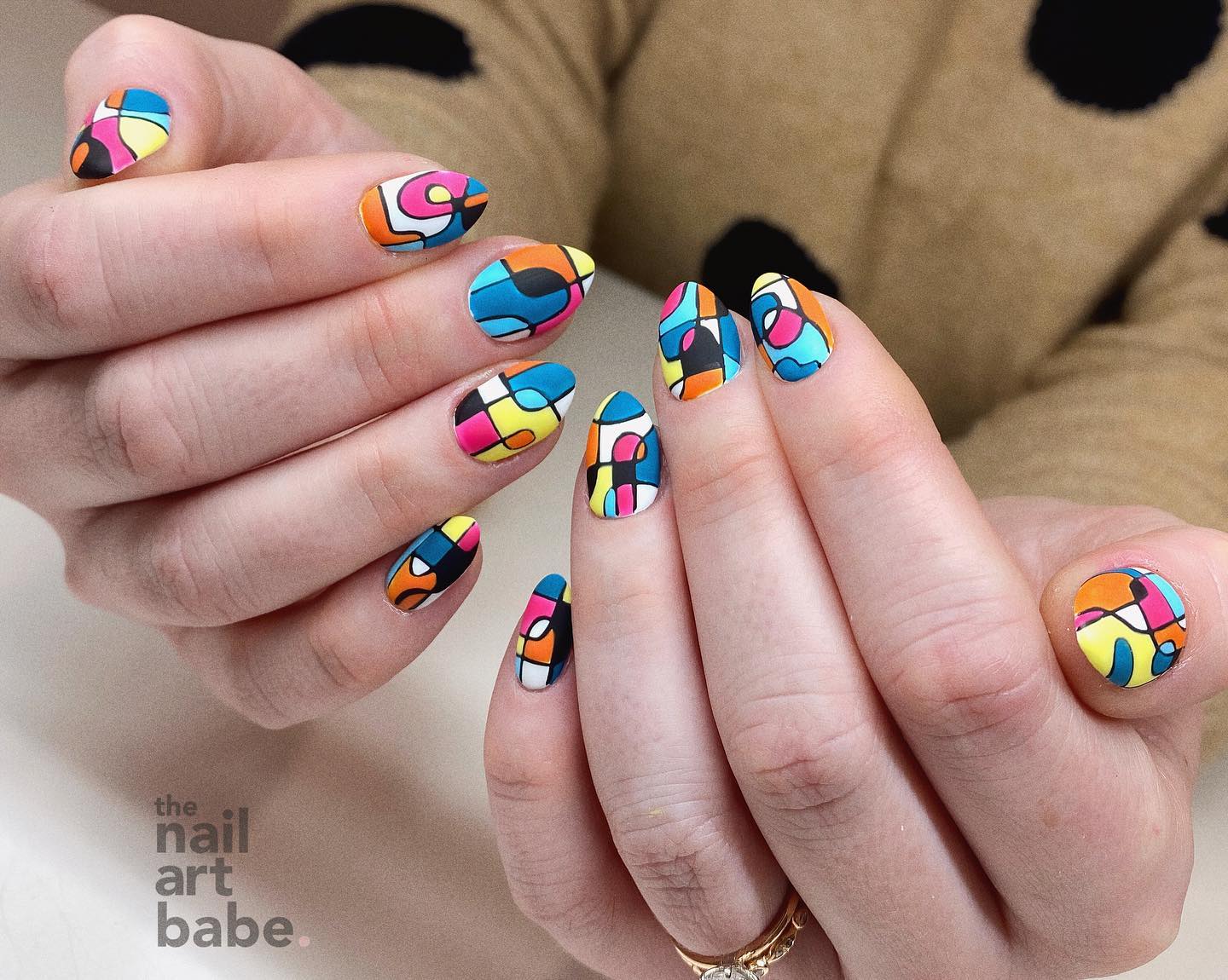 Multicolored geometric pattern in matte finish on short almond nails