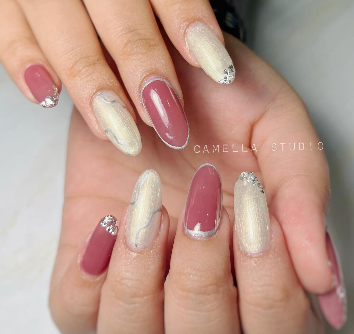 Pearl white and nude pink nail polish with silver foil and silver swirls on long almond nails