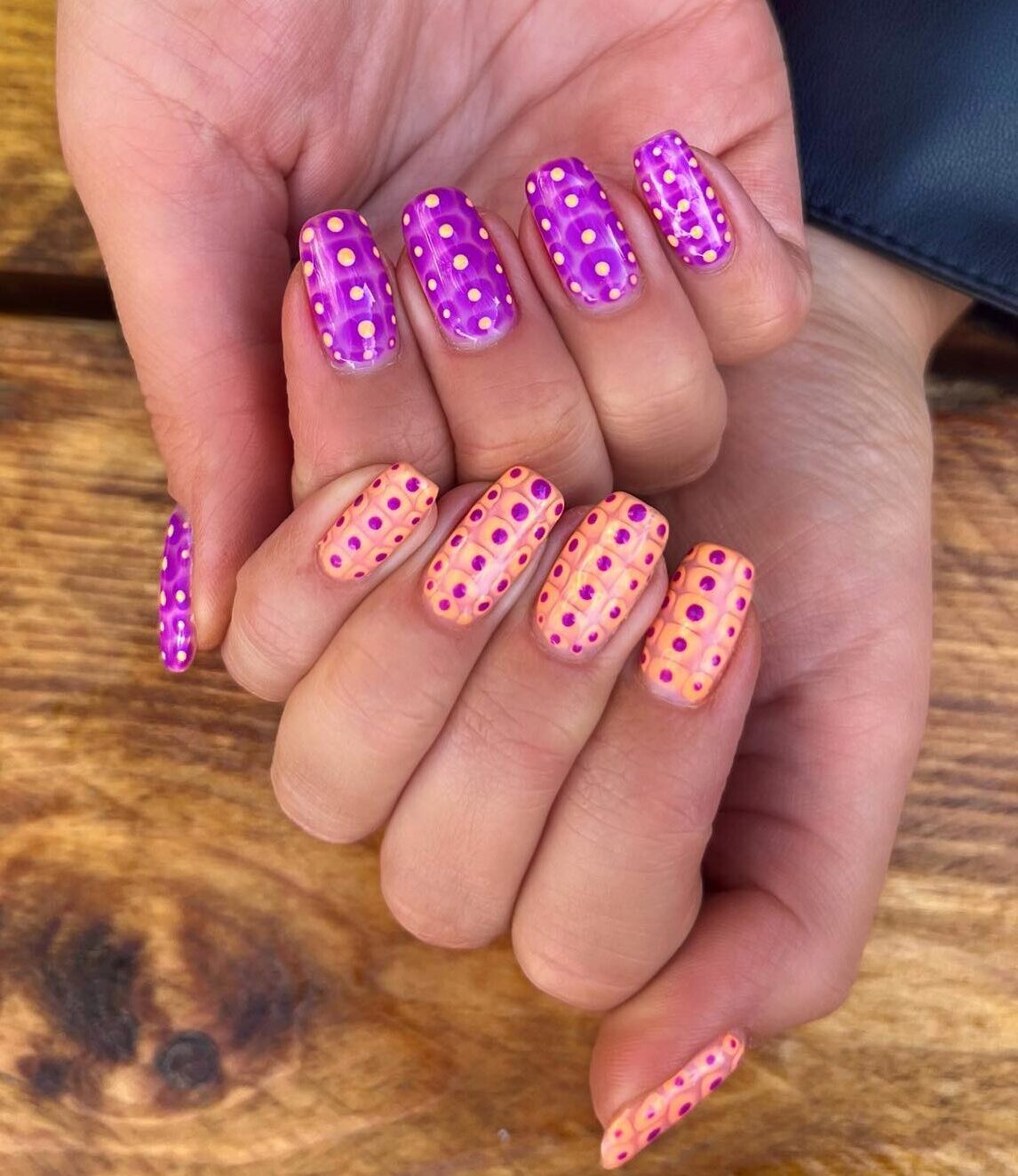 Bright purple and pale orange nail polish with polka dots nail art on short square nails