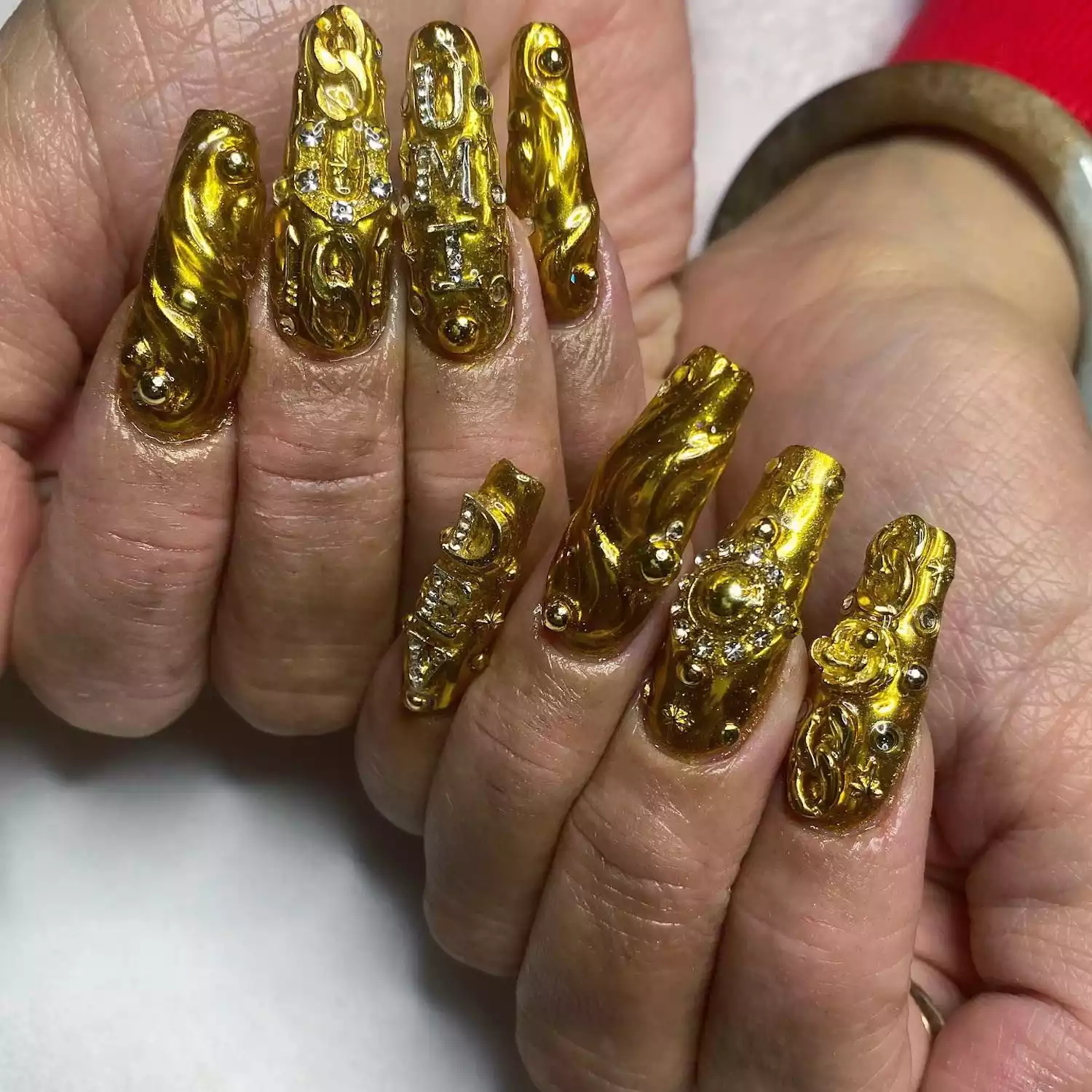 Gold manicure with 3D metallic designs and long square tips