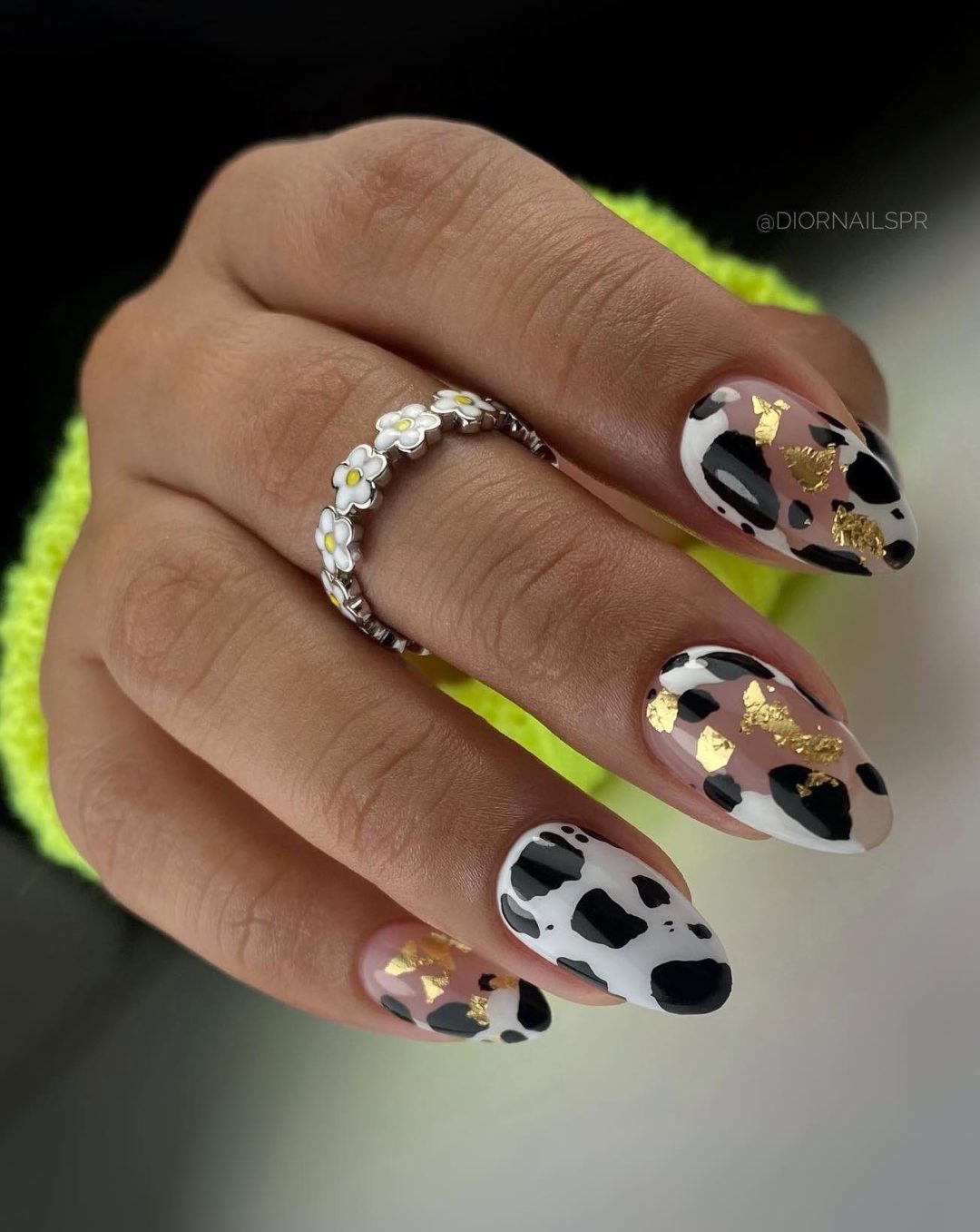 Black and white cow print nails with gold flakes.