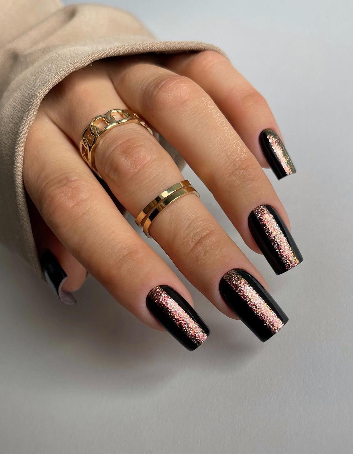 Long black nails with rose gold glitter.