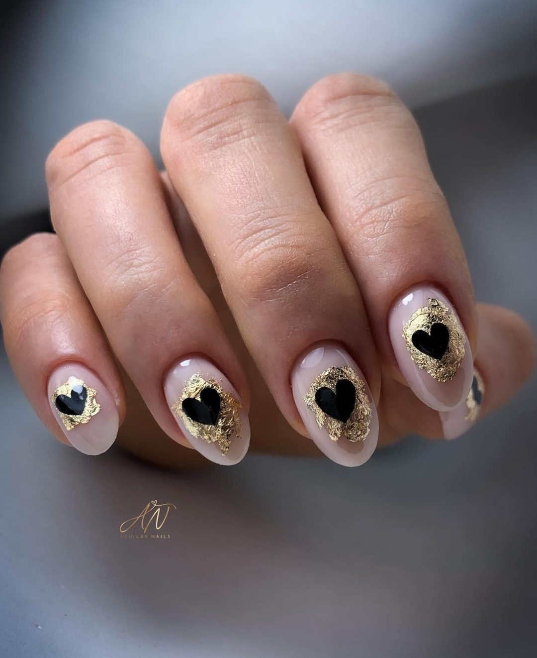 Clear nails with gold foil and black hearts.