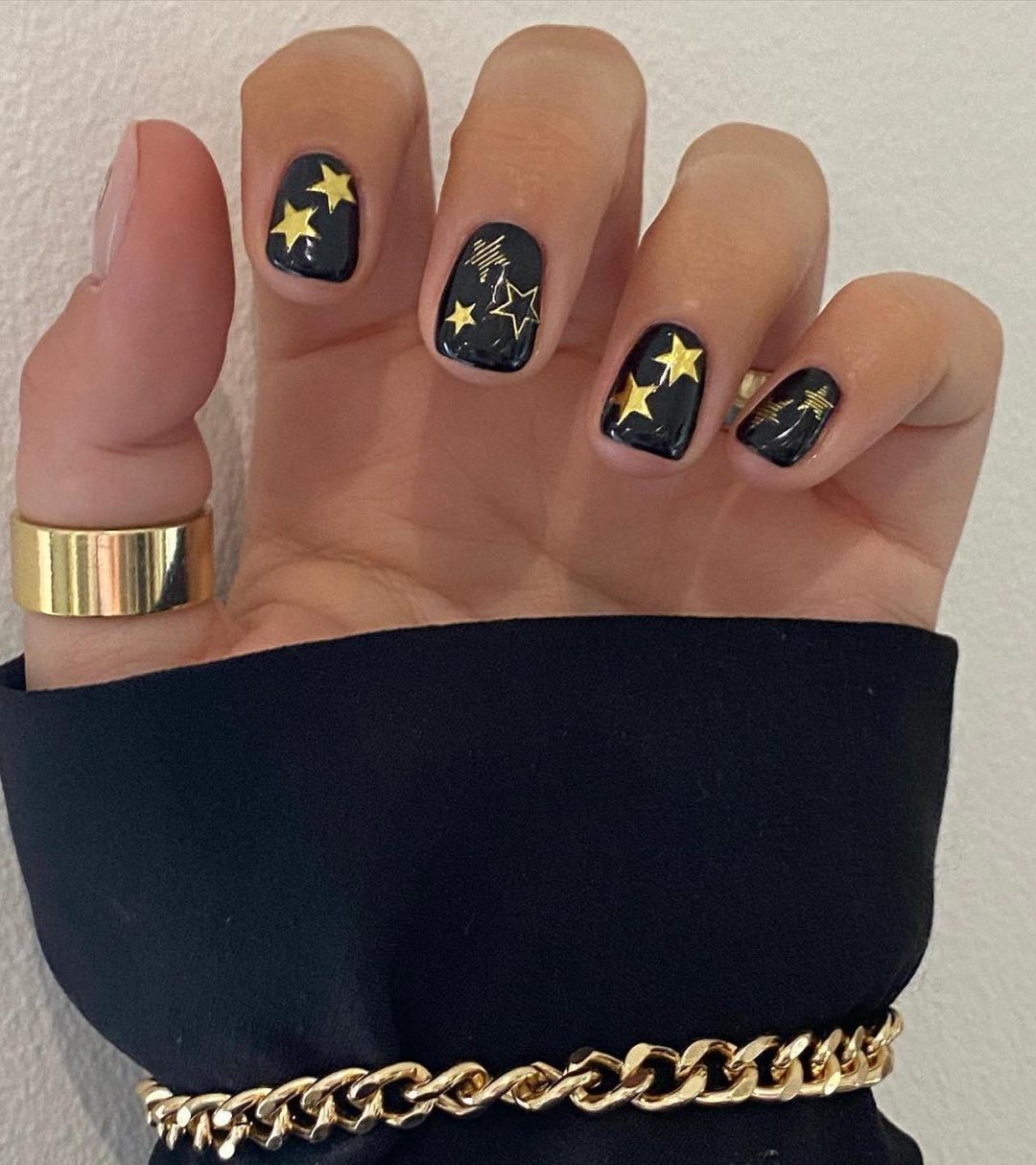 Short black nails with gold stars.