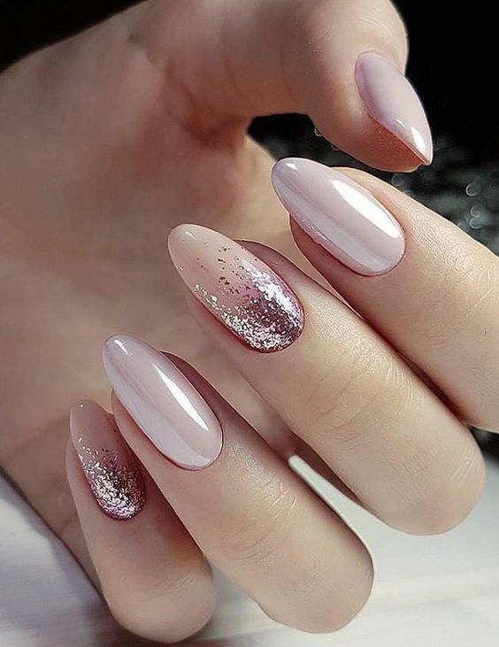 Glossy pale pink nail polish with pink glitters on medium round nails