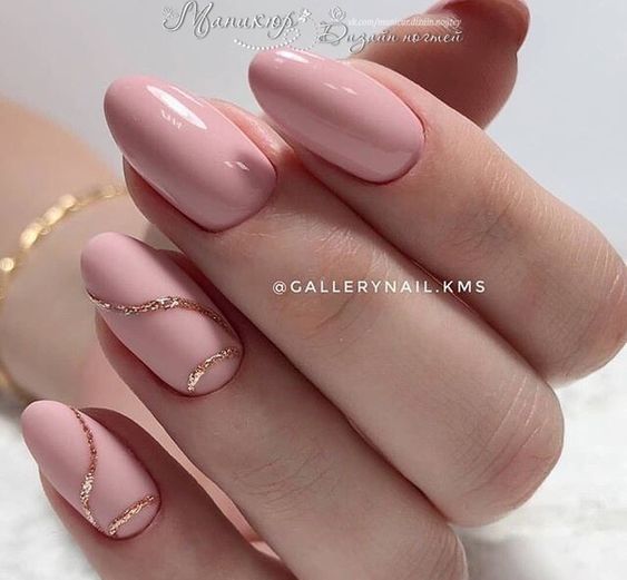 Light pink nail polish with gold swirls on short round nails
