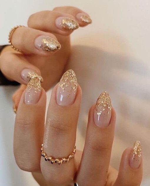 Clear almond shape nails with with gold glitters on the tips
