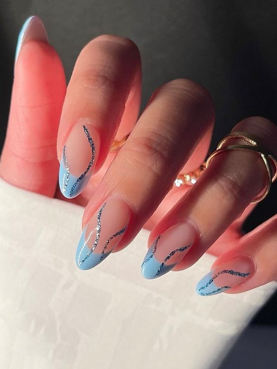Light blue French tips with blue sparkling swirls on medium almond nails